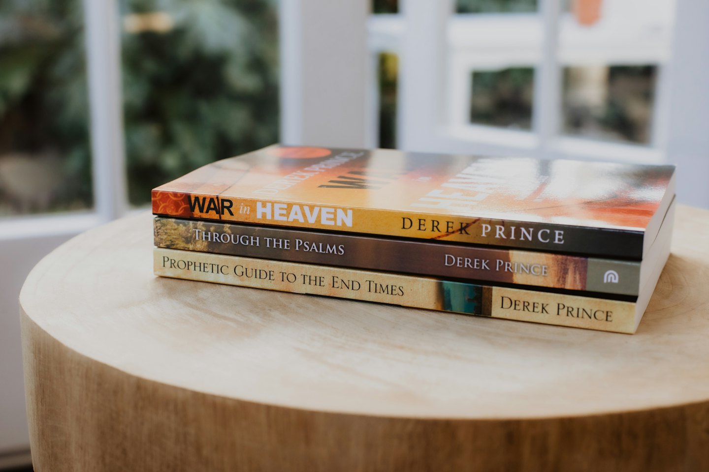 Three books stacked on a round wooden side table.